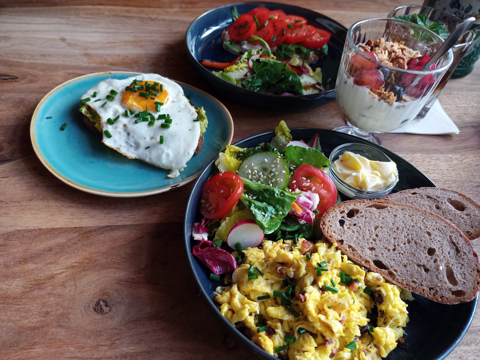 Bild zeigt mehrere Teller mit Eierspeisen und Gemüse sowie ein Glas mit Joghurt