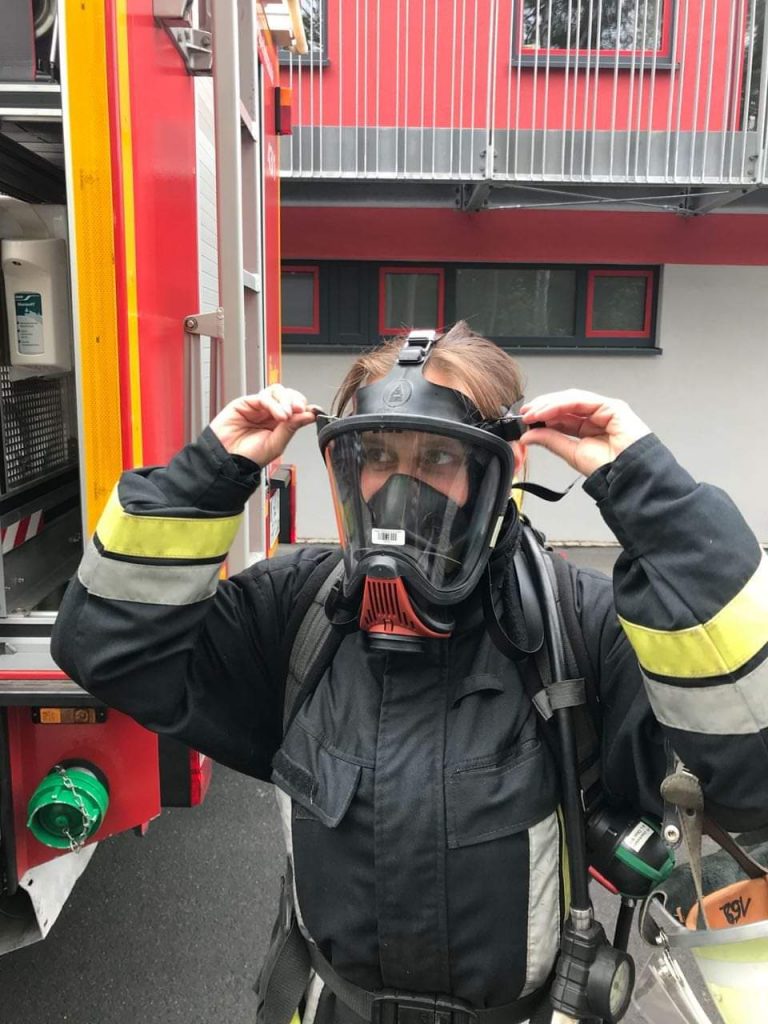 Das Foto zeigt die ehrenamtliche Feuerwehrfrau Michaela Poß mit einer Atemschutzmaske.