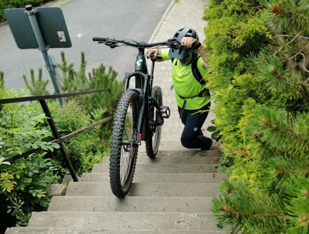 Frau schiebt Rad eine Treppe hinauf