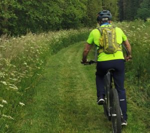 Fahrradfahrerin fährt über einen frisch gemähten Feldweg bei einer Landkreisumrundung