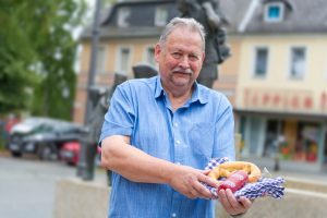 Gästeführer im Hofer Land, Wolfgang Pollnick, zeigt eine Breze und eine Rindfleischwurst bei der Stadtführung durch das Hofer land