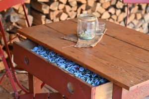 Ein Tisch, in dessen Schublade eine große Sammlung an blauen Bierdeckeln liegt