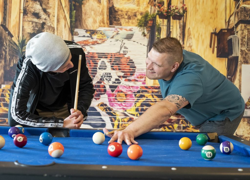 Jugendlicher und Betreuer spielen Billard