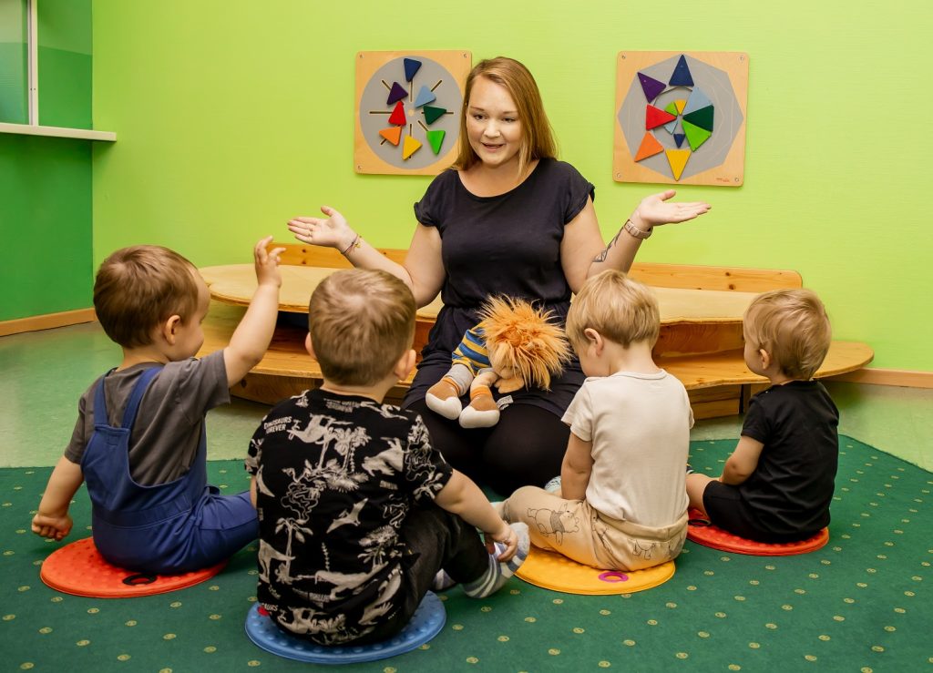 Erzieherin sitzt im Kreis mit den Kindern