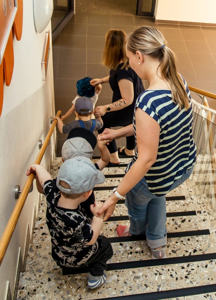 Erzieherinnen führen Kinder die Treppe herunter