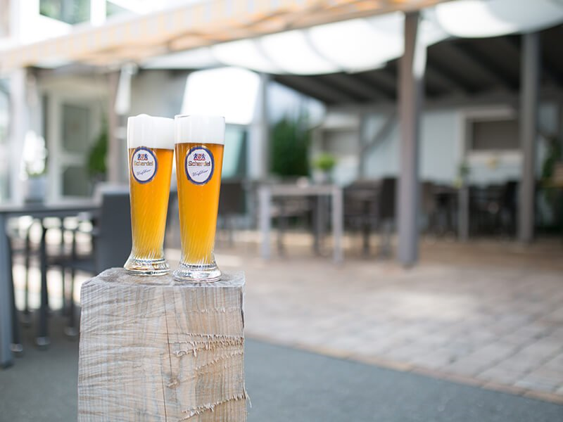 Zwei Weißbier, im Hintergrund der Biergarten des Landgasthof Grüne Linde in Wölbattendorf