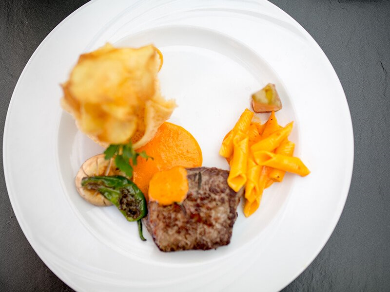 Steak, Pasta und Gemüse auf einem weißen Teller angerichtet