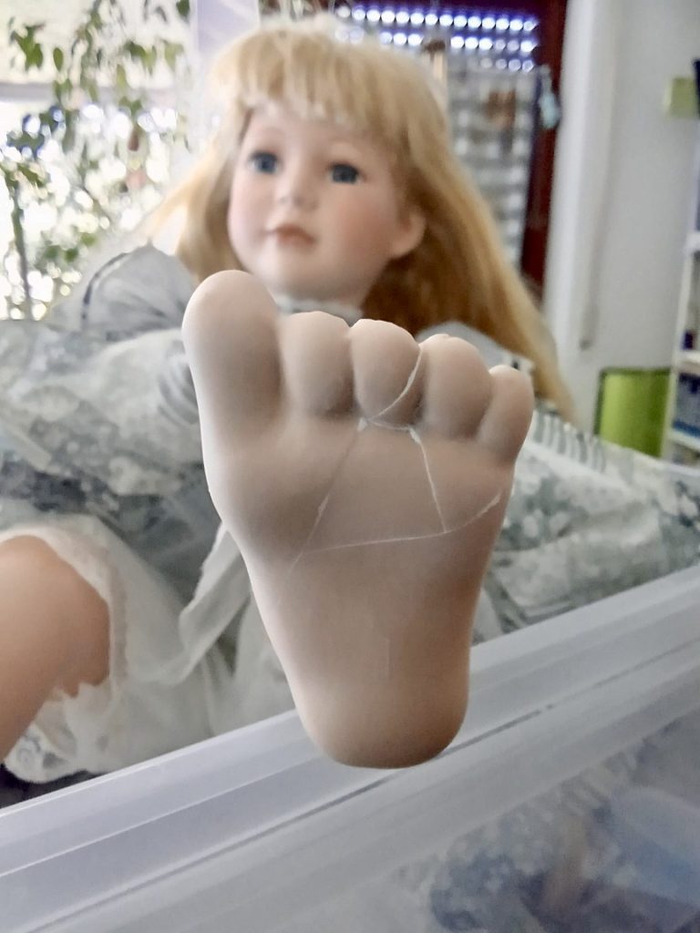 Porzellanpuppe mit zerbrochenem Fuß